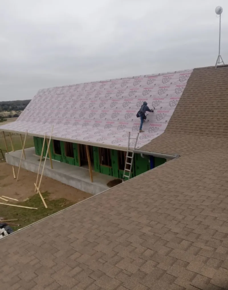 Worker preparing underlayment for a metal roof installation in Spring Lake Park